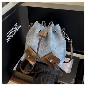 Detail shot of vintage denim bucket bag showing leather drawstring and textured fabric