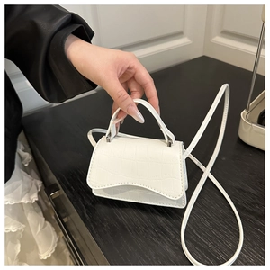 Detail view of white crocodile pattern mini bag with top handle and shoulder strap