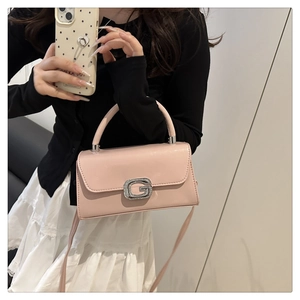 Detail of pink faux leather handbag with a diamond-encrusted G-buckle and top handle
