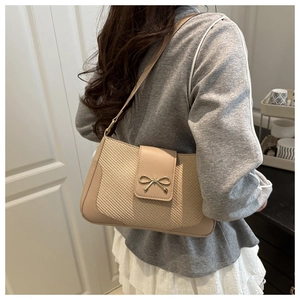 Détail du sac à bandoulière abricot avec boucle nœud doré et panneaux à texture tissée