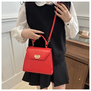 Detail of red leather trapezoid bag with gold square buckle shown on a model