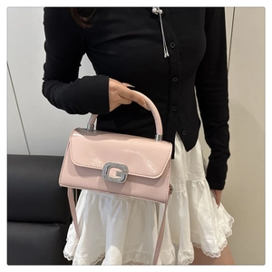 Detail of pink patent leather handbag featuring a crystal-studded G-buckle lock
