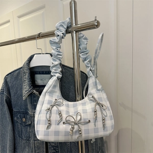 Blue and white checkered hobo bag with ruffled handle and bow details on denim