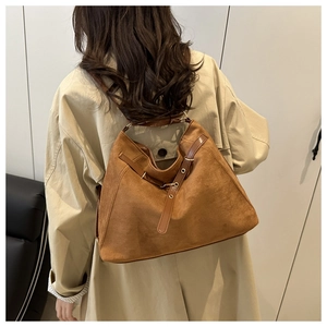 Detail view of brown faux suede tote bag featuring fine stitching and metal buckles