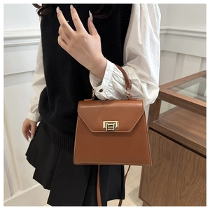 Close-up of brown textured leather handbag with gold twist lock and elegant top handle