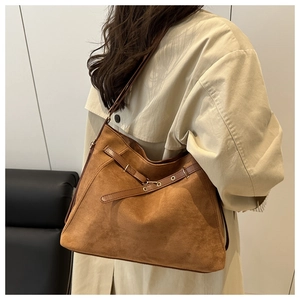Detail shot of brown suede tote bag featuring adjustable strap and elegant gold hardware