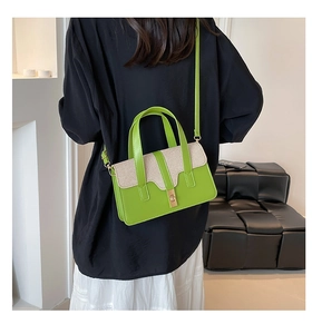 Détail du sac en cuir vert et beige tissé avec fermoir doré porté par un mannequin
