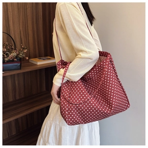 Detailed view of red polka dot canvas tote bag with long straps worn on shoulder
