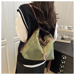 Detail of green suede tote bag with brown leather trim shown from a side-carrying angle