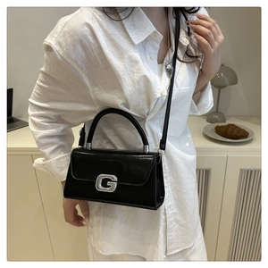 Close-up of black glossy leather bag featuring a silver rhinestone G-buckle and handle