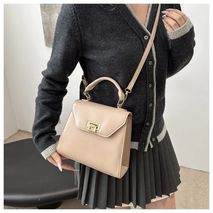 Detail of a beige crossbody bag with a gold square rotary lock and thick handle
