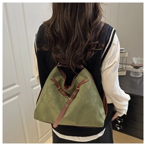 Detailed view of forest green suede bag with brown leather strap and metal buckle