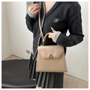 Detail view of khaki faux leather shoulder bag with gold metal clasp on model attire