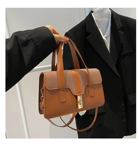 Detail of caramel faux leather bag with woven flap and golden rectangular twist lock