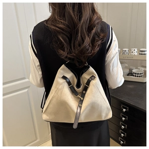 Beige matte textured backpack featuring black leather straps and gold hardware on model