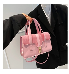 Detailed close-up of a pink shoulder bag featuring a woven texture and gold metal lock