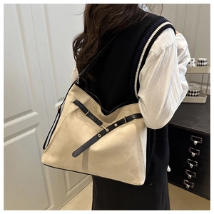 Detail view of a large cream tote bag featuring black leather straps and gold buckle