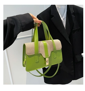 Detail of lime green leather and beige canvas handbag with metallic turn-lock closure