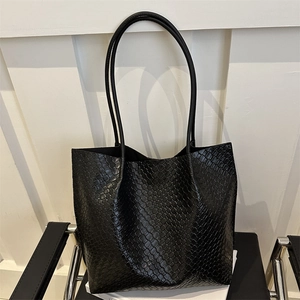 Black woven texture tote bag with leather straps on a chair, minimalist design style
