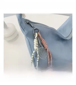 Detail of light blue shoulder bag featuring sporty tennis racket charm and rope zipper pull