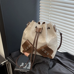 Chic canvas drawstring bucket bag with brown leather trim and stylish metal eyelets