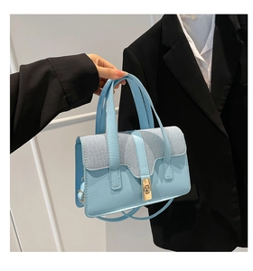 Close-up of light blue leather handbag showing gold twist lock and fine fabric texture