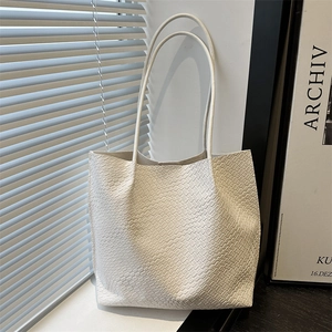 White woven tote bag with long handles in a minimalist interior with natural lighting