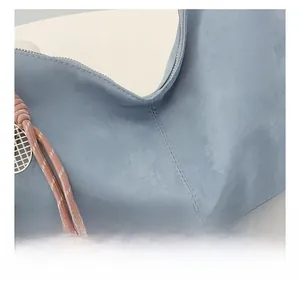 Detail of light blue textured shoulder bag with precision stitching and woven knot decor