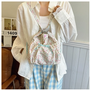 Detailed shot of floral canvas tote bag with blue checkered ribbon bow and drawstring closure