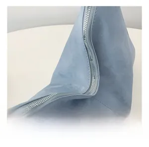 Detail view of smooth silver metal zipper on light blue tote bag with matte texture