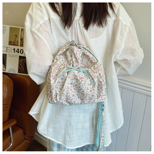 Detail of floral canvas bag featuring a blue checkered bow and pink button accents