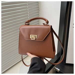 Close-up of brown PU leather bag with gold buckle and top handle in a modern room