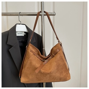 Détail du grand sac cabas en daim marron avec lanières en cuir et boucle dorée