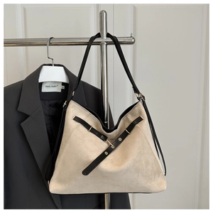 Détail du grand sac cabas en daim beige avec lanières en cuir noir et boucles dorées