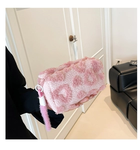 Detalle de bolsa de maquillaje de felpa rosa con pompón suave y cremallera metálica