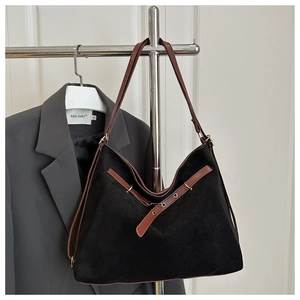 Détail du sac cabas en daim noir avec bretelles en cuir marron et boucles métalliques