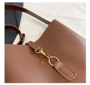 Close-up of vintage gold clasp and fine stitching on a brown leather bucket bag