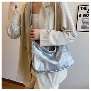 Detail of silver metallic hobo bag with adjustable strap worn with a beige blazer