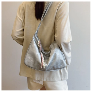 Detail of silver metallic tote bag with distressed texture and fringe charm on model