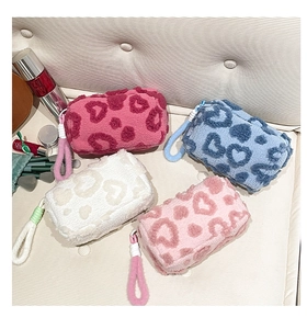 Macro detail of plush velvet pouches with 3D leopard heart patterns and woven lanyards