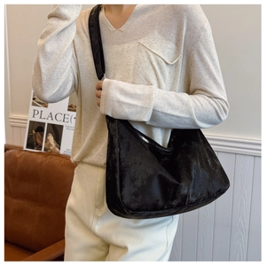Detailed view of the black oversized hobo shoulder bag shown on model in a cozy interior