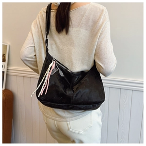 Detail view of black crescent shoulder bag with colorful rope tassels and silver hardware