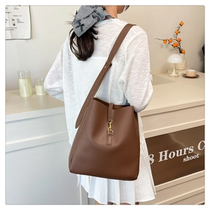 Detail of caramel leather bucket bag featuring a classic golden piston lock and long strap
