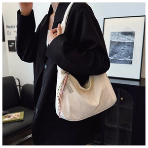 Close-up of off-white hobo bag featuring woven pendant and sleek metal hardware