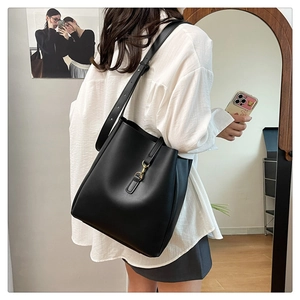 Side view of black matte leather bucket bag with gold hook on a female model