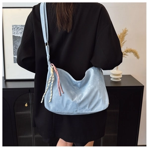 Detail of light blue hobo bag with braided rope charm and matte texture on model