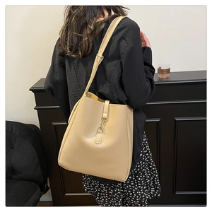 Detailed back view of model wearing a large beige bucket bag with leather texture