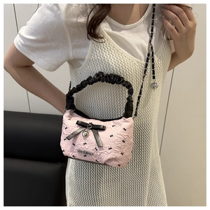 Detail of pink bow handbag featuring a metal heart pendant and fashion plaque