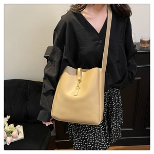 Detail of beige faux leather bucket bag with elegant gold metal buckle closure