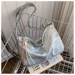 Detail of silver metallic hobo bag with tennis racket charm and rope knot zipper pulls